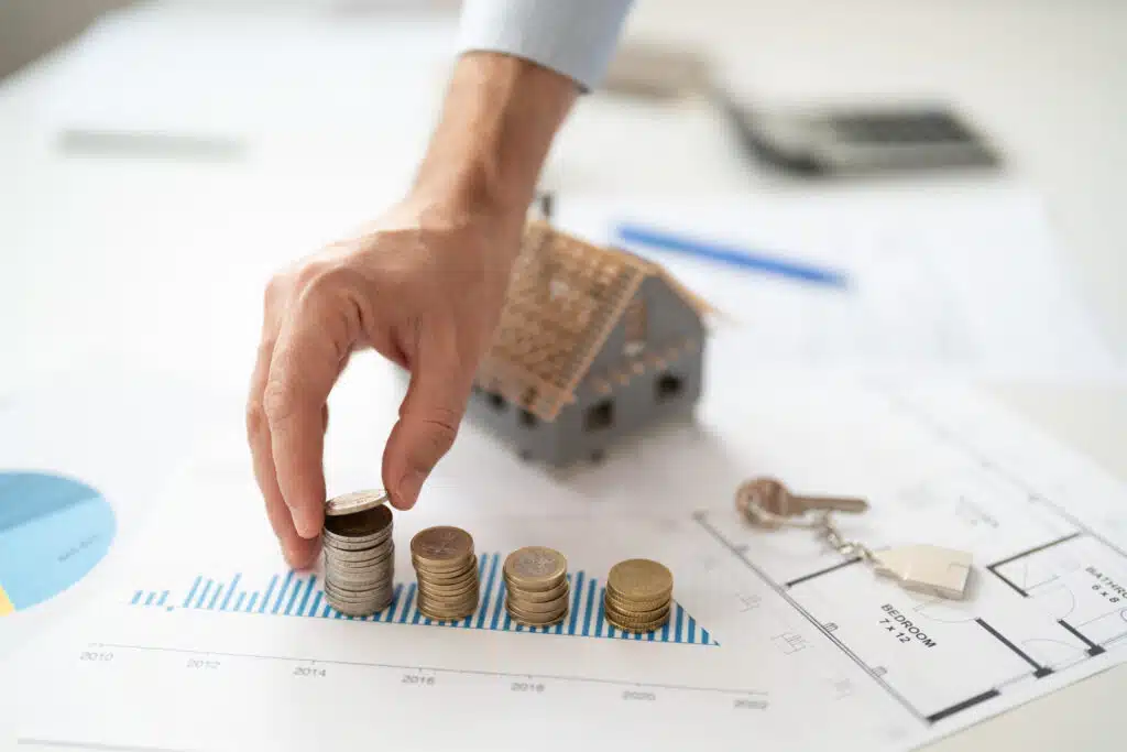 Property management fees in Phuket illustrated by stacked coins, house model, and financial chart showing rental investment growth and cost analysis.