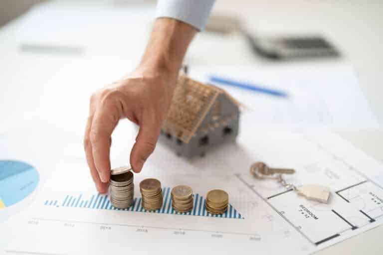 Property management fees in Phuket illustrated by stacked coins, house model, and financial chart showing rental investment growth and cost analysis.