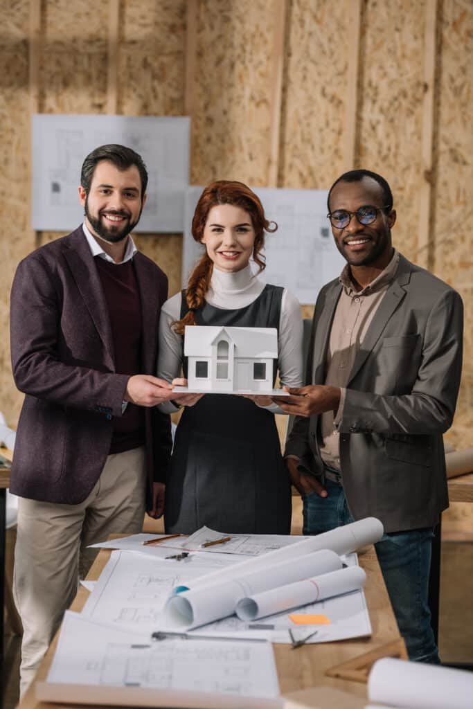 Architects holding a miniature house model.