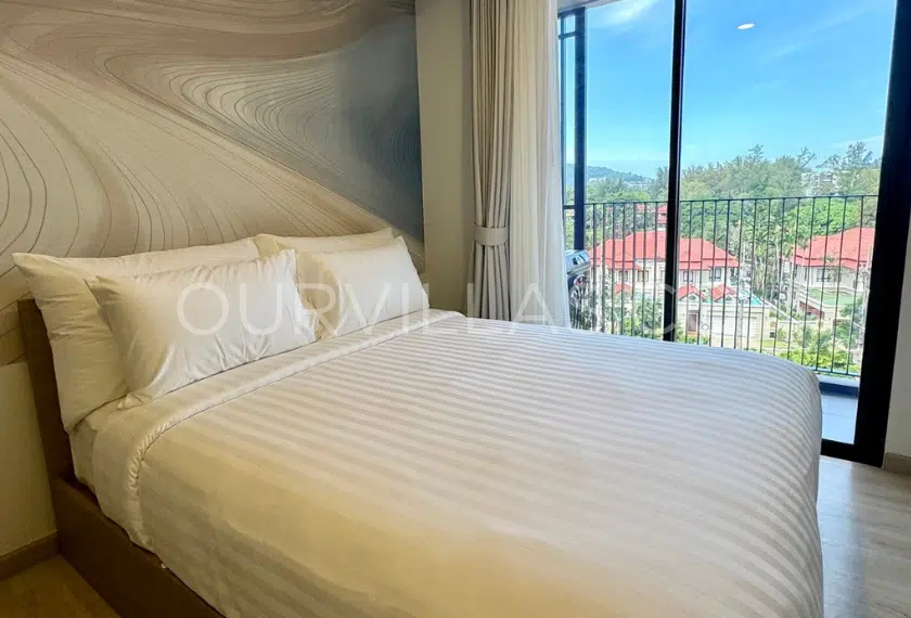 Modern bedroom with a scenic balcony view in Skypark Phuket.