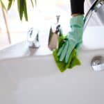 deep cleaning in Phuket: A person cleaning a bathroom faucet with gloves.