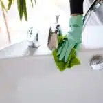 deep cleaning in Phuket: A person cleaning a bathroom faucet with gloves.