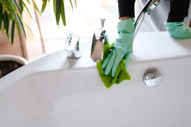 deep cleaning in Phuket: A person cleaning a bathroom faucet with gloves.