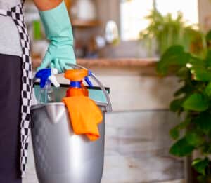 Home Deep Cleaning Services in Phuket: Cleaning supplies in a bucket with spray bottles and gloves.