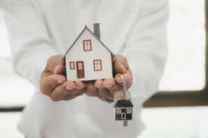 Can Foreigners Buy Property in Thailand: A person holding a house model and keys.