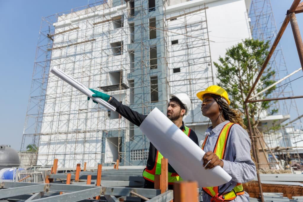 Building Restrictions in Phuket: Two civil engineers inspecting construction site with building plans in hand.