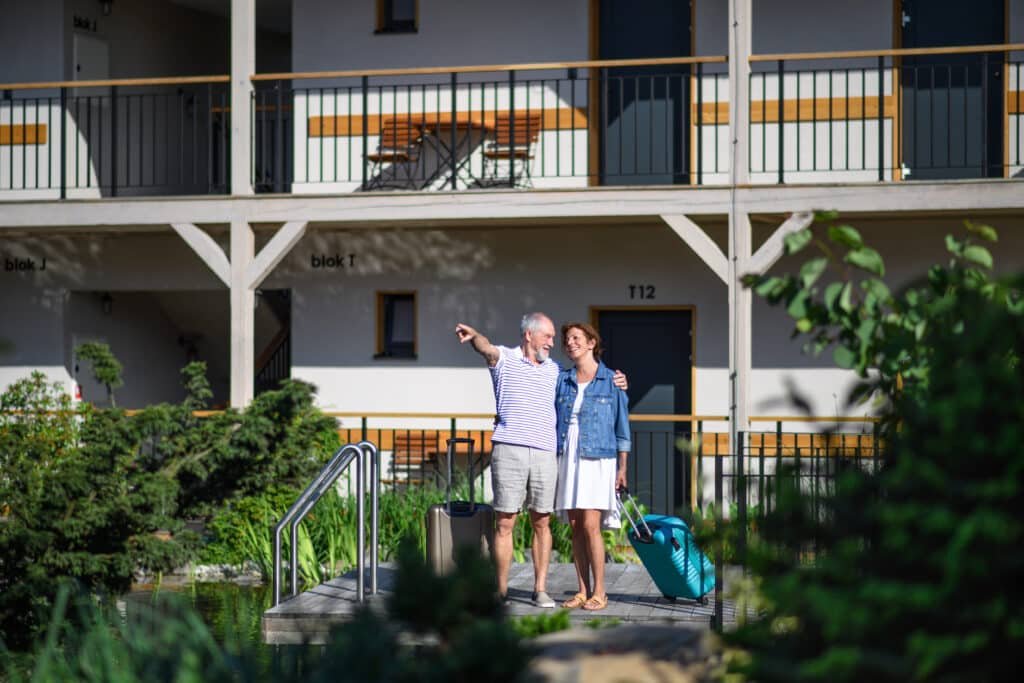 Property for Retirement in Phuket: Happy senior couple standing outside a holiday apartment.