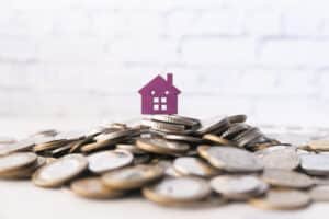 Investment Property in Thailand: Miniature house figure on top of a stack of coins representing real estate investment.