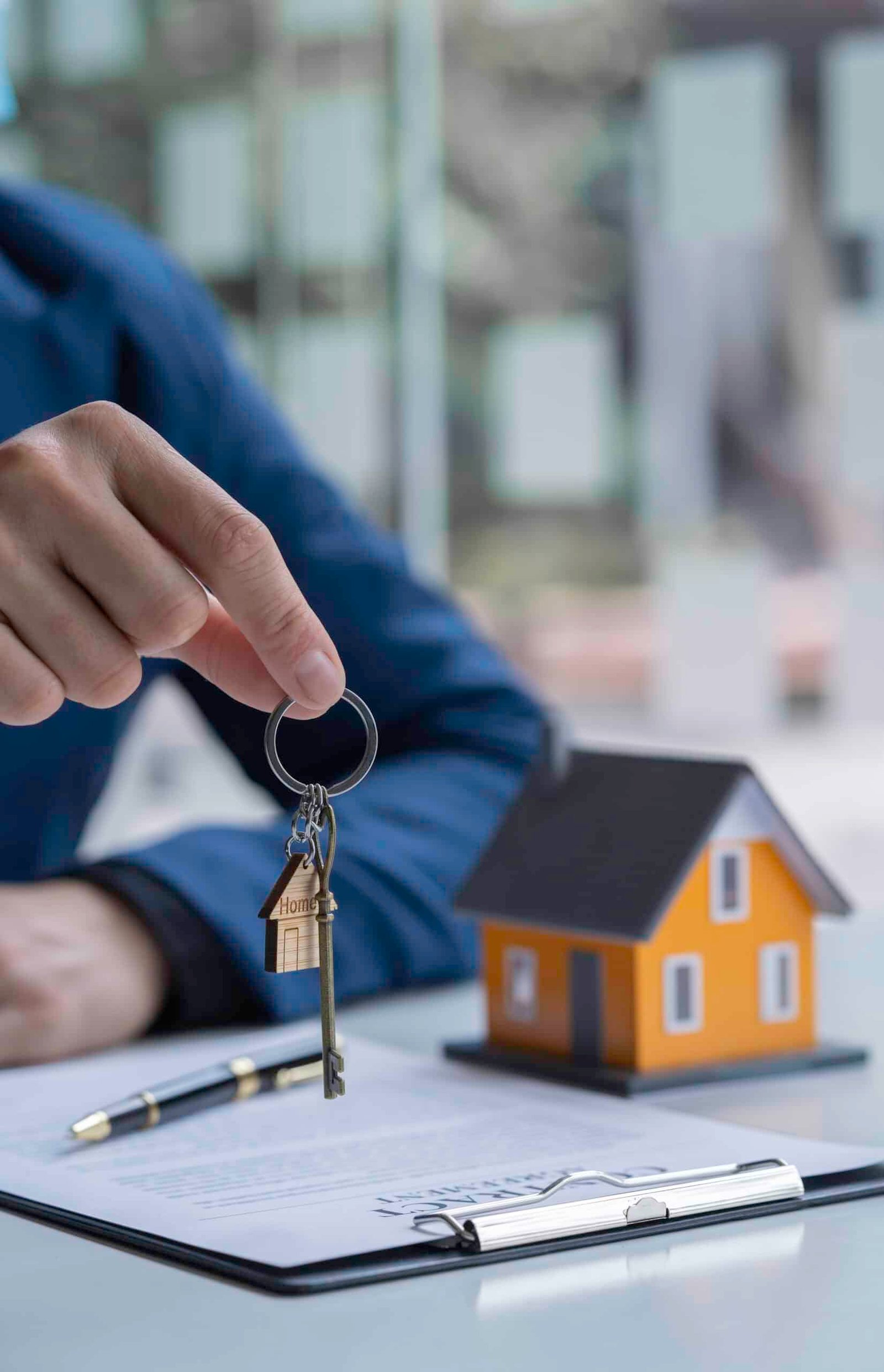 Property manager handing over house keys beside a model home, representing trusted property management services and landlord support in Phuket.