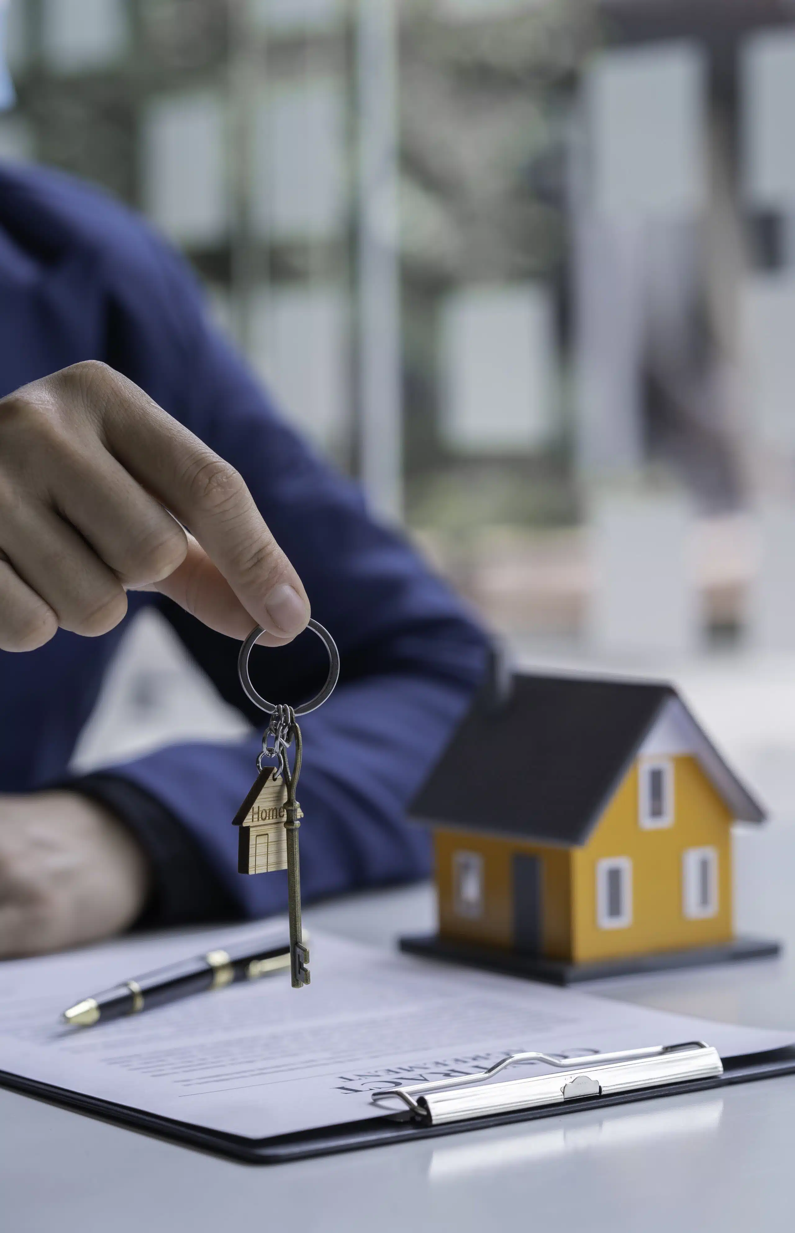 Property manager handing over house keys beside a model home, representing trusted property management services and landlord support in Phuket.